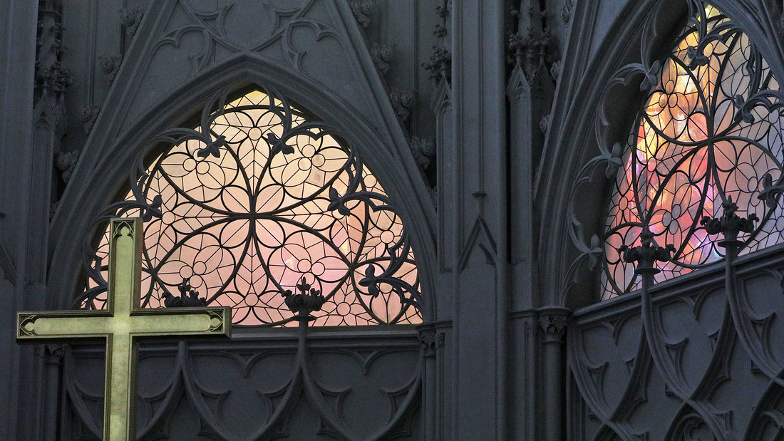 Kirchenfenster im Greifswalder Dom mit einem Kreuz davor.