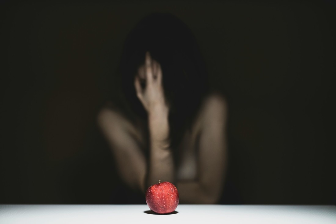 Eine Frau am Tisch, auf dem ein Apfel liegt