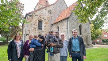Gruppe von Helfern und Flüchtlingen vor evangelischen Kirche in Schale