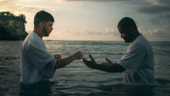 Zwei Männer stehen im Meer und führen eine Taufe durch