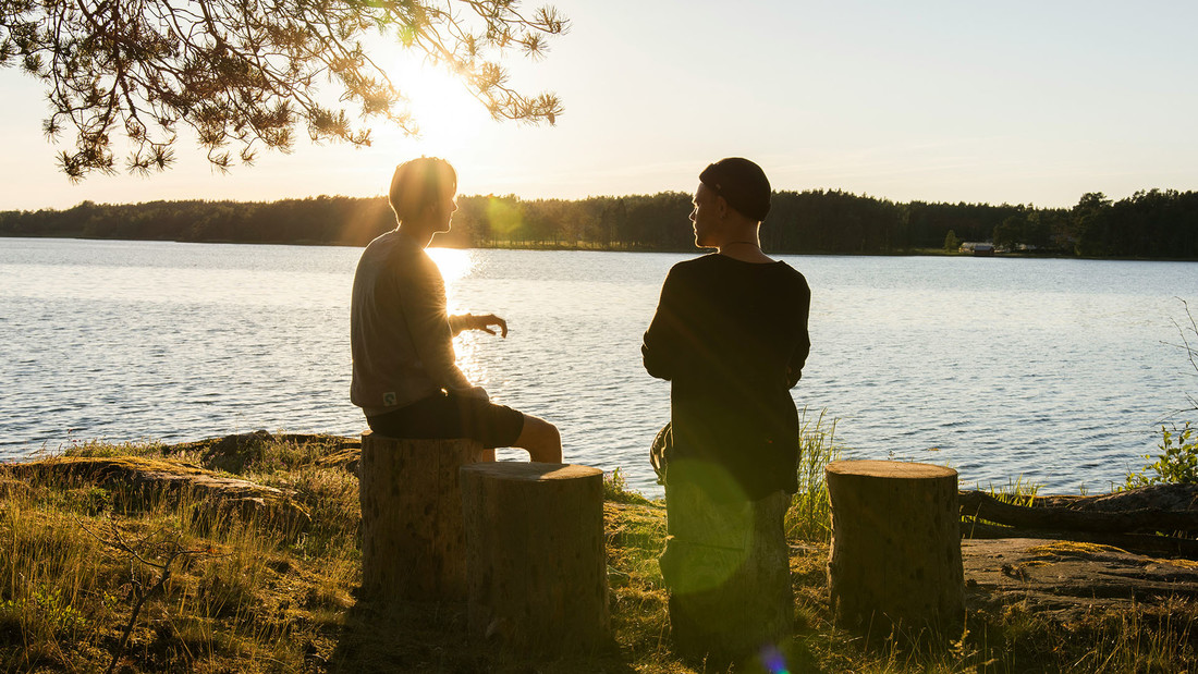 Zwei junge Männer sizten am See un unterhalten sich.
