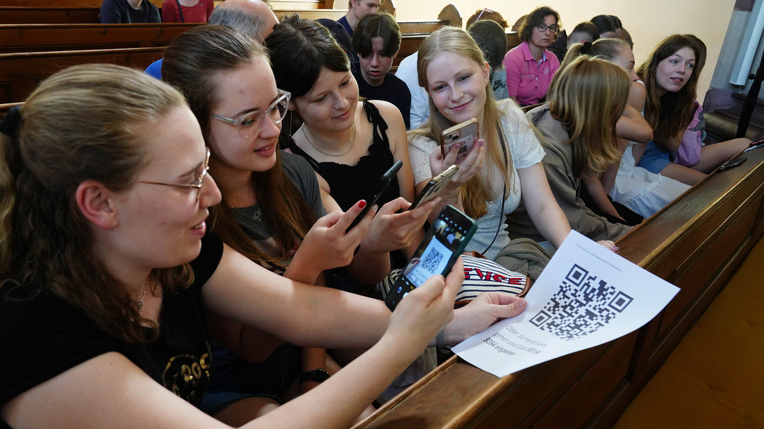 Jugendliche sitzten auf Kirchenbänken und loggen sich mit ihren Handys ein