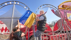Leyla Mak und Gino Frank befestigen ukrainische Fahnen vor dem Zelt des "Moskauer Circus" 