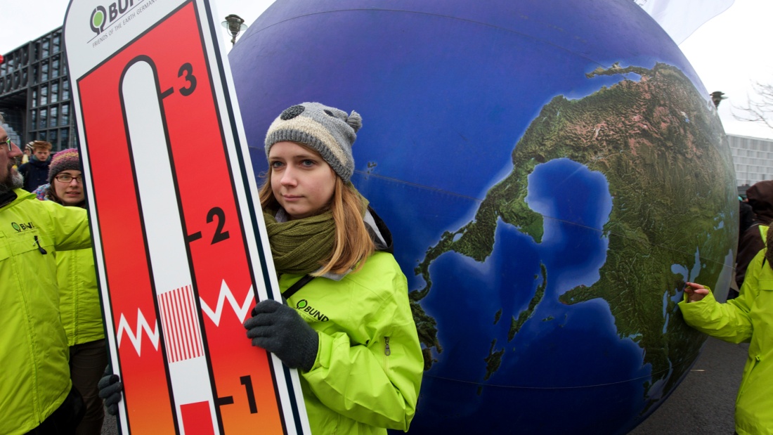 Protestierende hält ein riesiges Thermometer mit dem 1,5 Grad Ziel in der Hand 