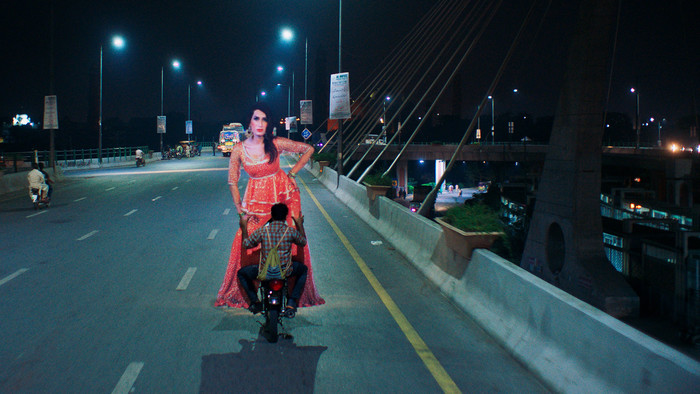 Die pakistanische Produktion "Joyland" macht erstmals Transpersonen sichtbar. Protagonist auf Moped mit überlebensgroßem Aufsteller einer Dragqueen