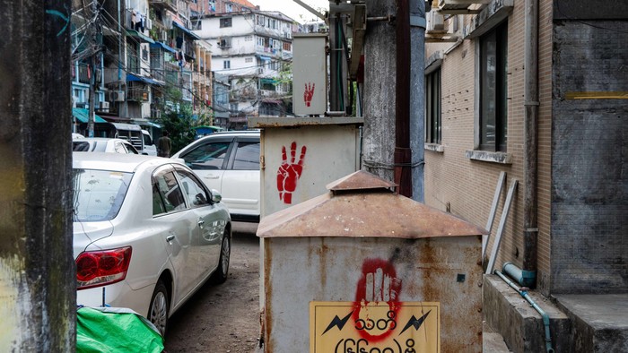 Eine Straße in Yangon, im Vordergrund aufgesprüht auf ein Trafo-Häuschen der Drei-Finger-Gruß