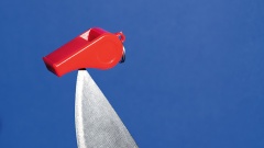Illustration: Eine rote Trillerpfeife ist auf einem Küchenmesser aufgespießt, vor blauem Hintergrund