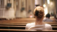 Frau von hinten sitzt allein in Kirche 
