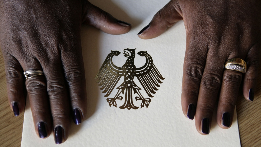 Die Hände einer Frau liegen auf der Einbürgerungsurkunde der Bundesrepublik Deutschland
