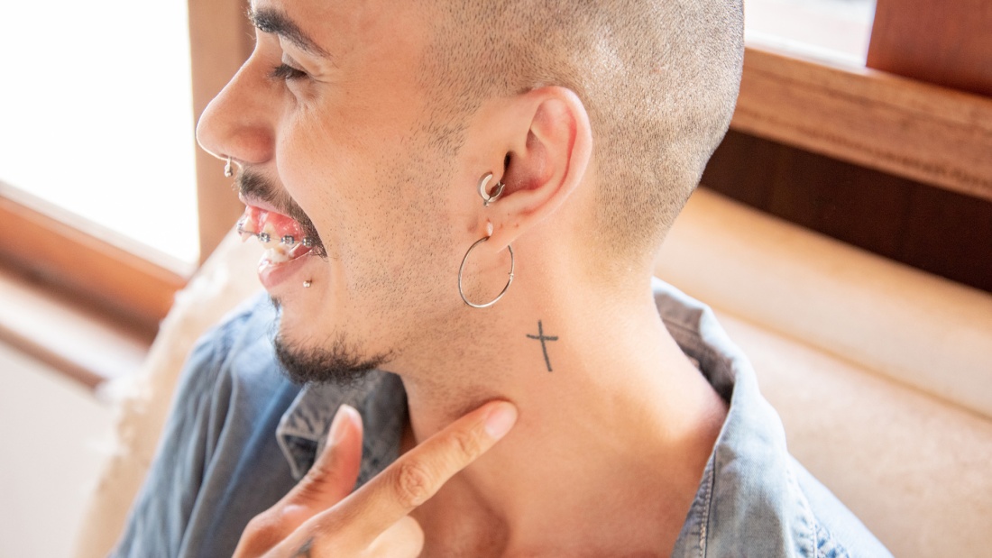 Mann mit Piercings und Kreuz Tattoovierung