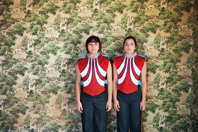 Zwei Schwestern in Marfa, Texas tragen die Uniform einer Blaskapelle und stehen vor eine opulenten Tapete