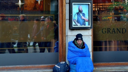 Ein Obdachloser sitzt auf dem Bürgersteig