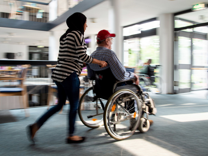 Duisburg: Eine Pflegerin mit Kopftuch schiebt im multikulturellen Seniorenzentrum "Haus am Sandberg" vom Deutschen Roten Kreuz einen Bewohner im Rollstuhl
