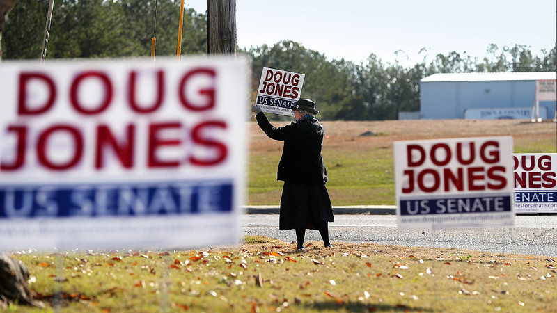 Eine Anhängerin des Demokraten Doug Jones hält aam Straßenrand ein Schild mit der Aufschrift Doug Jones für den US Senat nach oben.