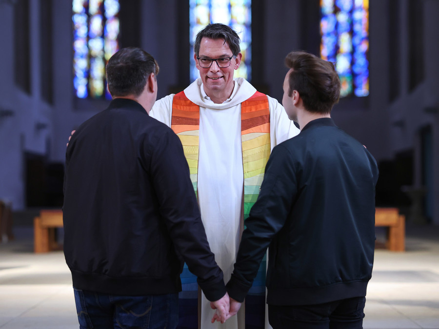Pfarrer Christoph Kunz segnet während einer Segnungsfeier das queere Paar Falko (l) und Dennés (r) in der Bischofskirche Sankt Sebastian des katholischen Bistums Magdeburg