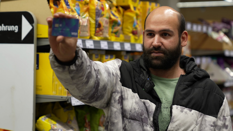 Ein Asylbewerber hält seine Socialcard in die Kamera