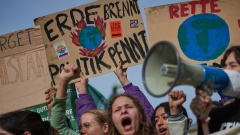 Aktivist:innen und Unterstützer:innen der Klimaschutzbewegung "Fridays for Future" halten Transparente bei einer Demonstration in die Höhe.