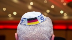 Bei einer jüdischen Veranstaltung trägt ein Teilnehmer eine Kippa mit eingearbeiteten israelischen und deutschen Fahnen.