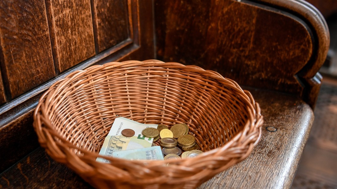Ein Korb mit Geldscheinen und Münzen steht in einer Kirche