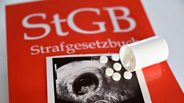 Ultraschallbild einer Schwangerschaft mit Tabletten auf einem Strafgesetzbuch.