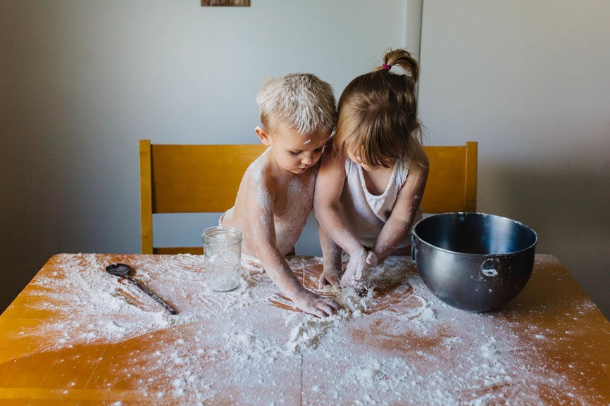Ein Mädchen und ein Junge machen Quatsch. Sie spielen mit Mehl.
