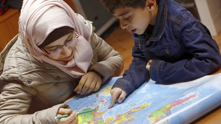 Die syrische Mutter Yasmine studiert mit ihren Sohn Hussein in einer kirchlichen Einrichtung in Rom eine Weltkarte.