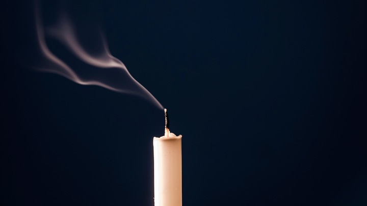 Rauch steigt von dem erloschenen Docht einr Kerze auf.