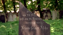 Zerbrochener jüdischer Grabstein mit dem Schriftzug "Friede seiner Asche" am jüdischen Friedhof in Berlin-Prenzlauer Berg.
