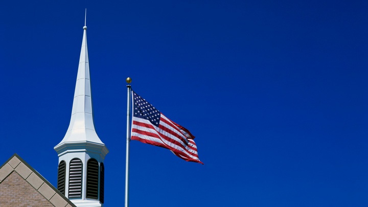 Die US-amerikanische Flagge weht neben einem Kirchturm, Utah, USA.