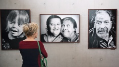 Besucherin blickt in der Ausstellung "Wir sind viele" auf Porträts von Menschen aus Bethel.