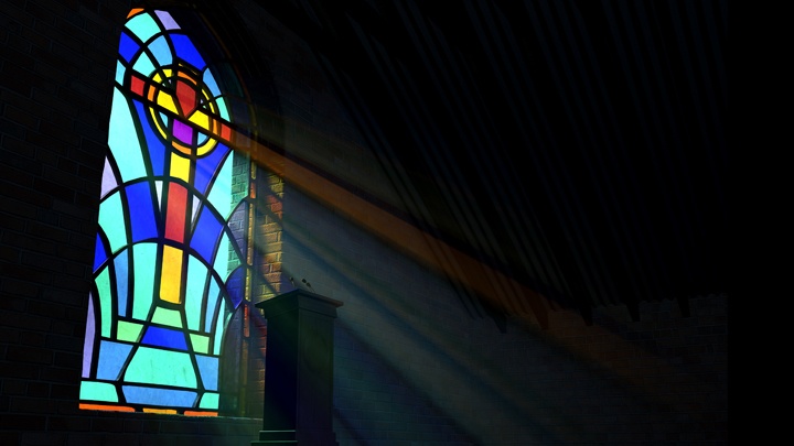 Lichtstrahlen fallen durch ein buntes Fenster auf ein leeres Pult in einer Kirche.
