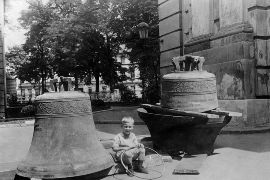 Ein Kind sitzt zwischen zwei Glocken.