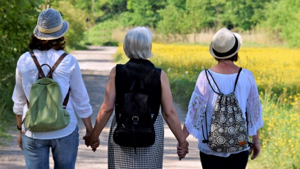 Drei Frauen gehen Hand in Hand spazieren