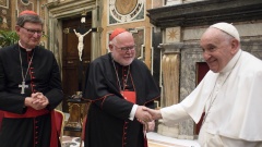 Papst Franziskus reicht Kardinal Marx die Hand, daneben Kardinal Woelki.