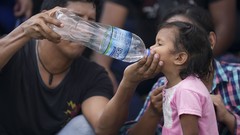 Ein Migrant gibt einem Kind Wasser während eines Halts auf der Flucht im Norden Mexikos