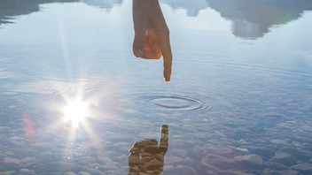 Finger berührt Wasseroberfläche