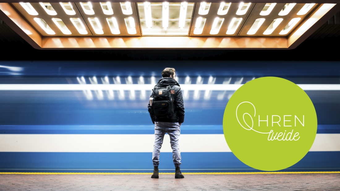 junger Mann steht in U-Bahnschacht während ein Zug vorbeifährt