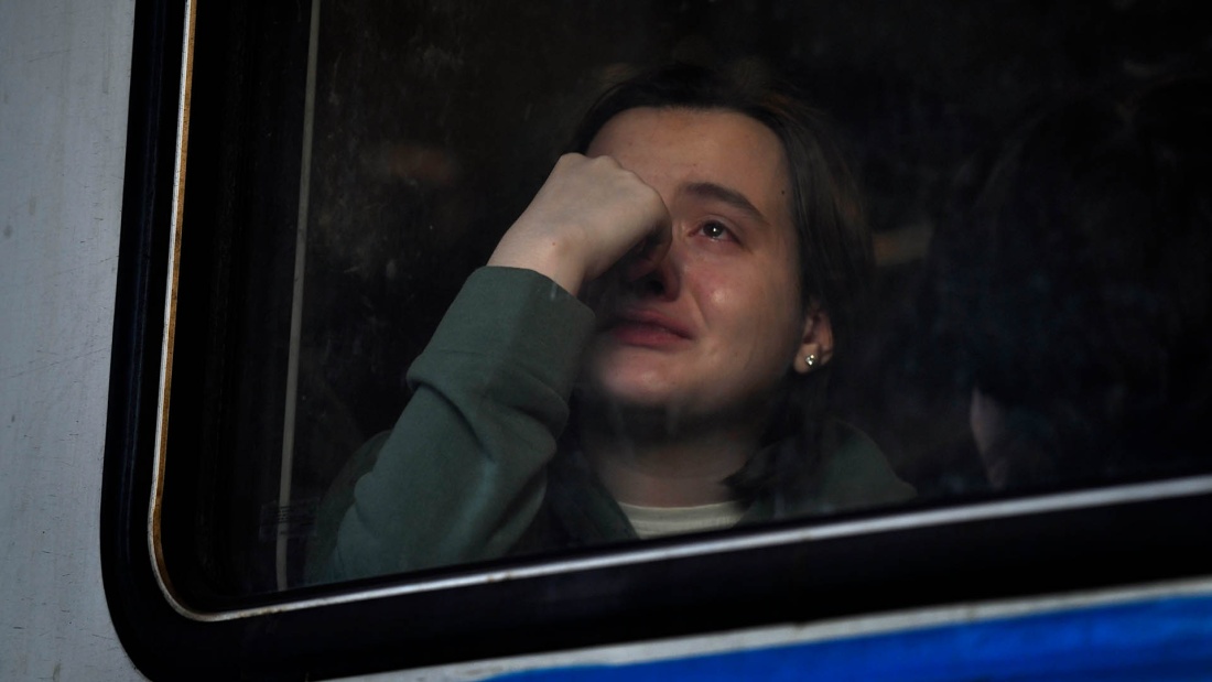 Flüchtlingsfrau sitzt weinend am Zugfenster