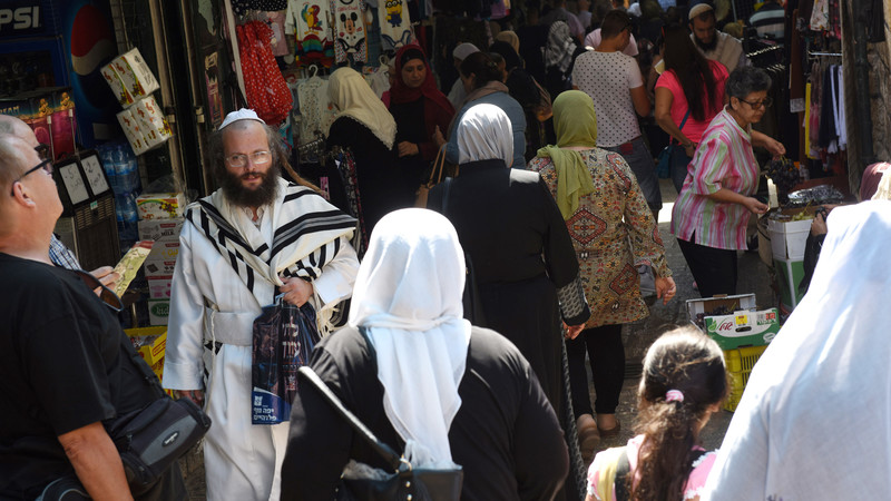 An Ultra-Orthodox Jew wears and white robe and prayer shawl while walking between Muslim women in the Old City of Jerusalem, on Rosh HaShanah, the Jewish New Year, and the Islamic New Year, September 21, 2017. Both religions follow the lunar calendar.