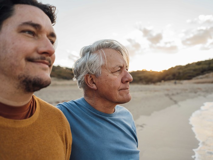 Vater und Sohn stehen am Strand und blicken auf das Wasser