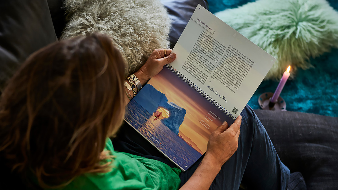 Eine Frau sitzt neben einer Kerze und hat einen aufgeschlagenen Kalender auf ihren Schoß.