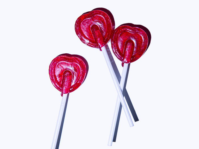 Drei rote Lollies in Herzform vor weißem Hintergrund