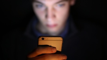 Junger Mann schaut auf seinen Smartphone-Bildschirm.