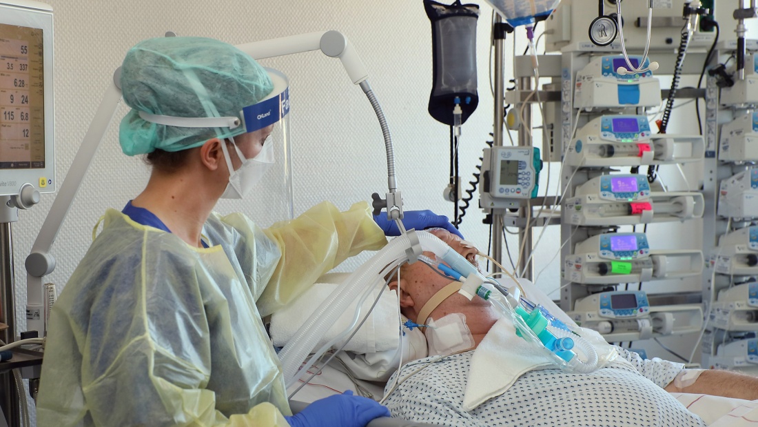 Pflegerin steht am Krankenhausbett einer Patienin in der Intensivemedizin