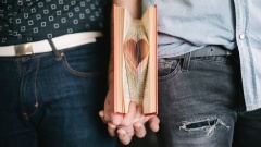 Homosexuelles Paar hält Händchen mit Buch