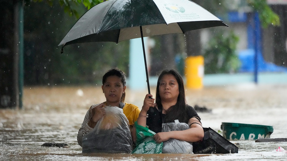 Anwohner schützen ihr Hab und Gut, während sie sich durch eine überflutete Straße kämpfen. Die Länder Philippinen, Indonesien und Indien sind "Risikohotspots" laut Weltrisikobericht.