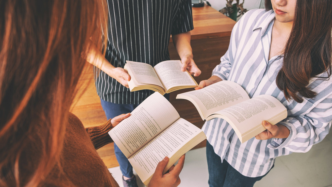 Jugendliche stehen im Kreis mit Büchern