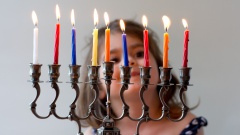 Ein Kind schaut die bunten Kerzen eines Chanukka-Leuchters an.