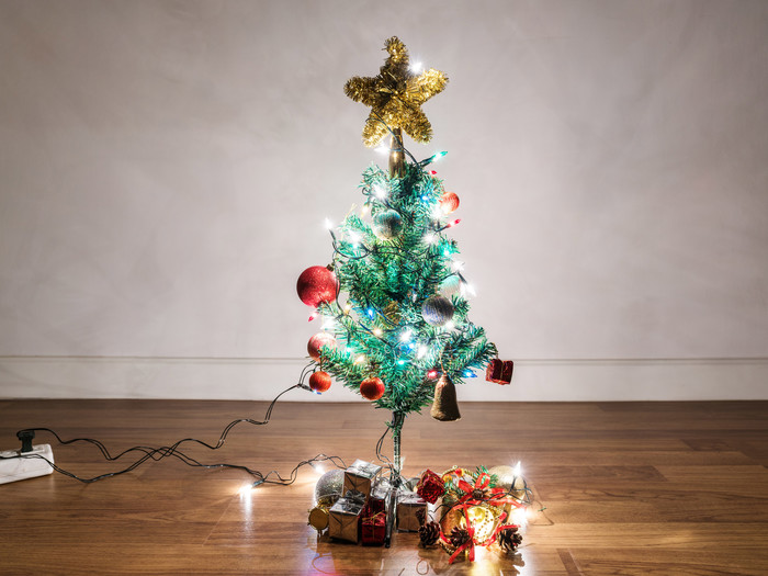 Weihnachtsbaumschmuck mit Weihnachtsgeschenken und Licht auf Holzboden im Wohnzimmer
