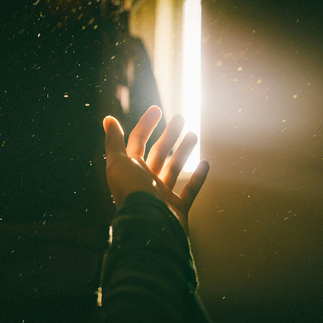 Hand  in Lichtstrahl mit Staubpartikeln im Licht